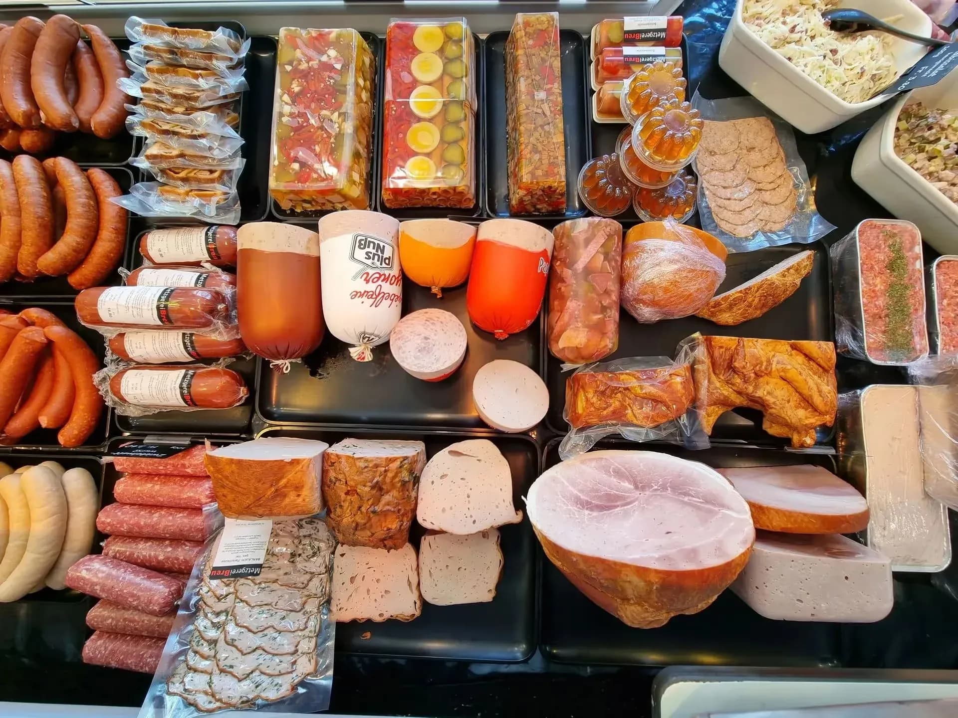 Gefüllte Auslage der Metzgerei Breu mit Würsten, Fleischkäse und Aufschnitt